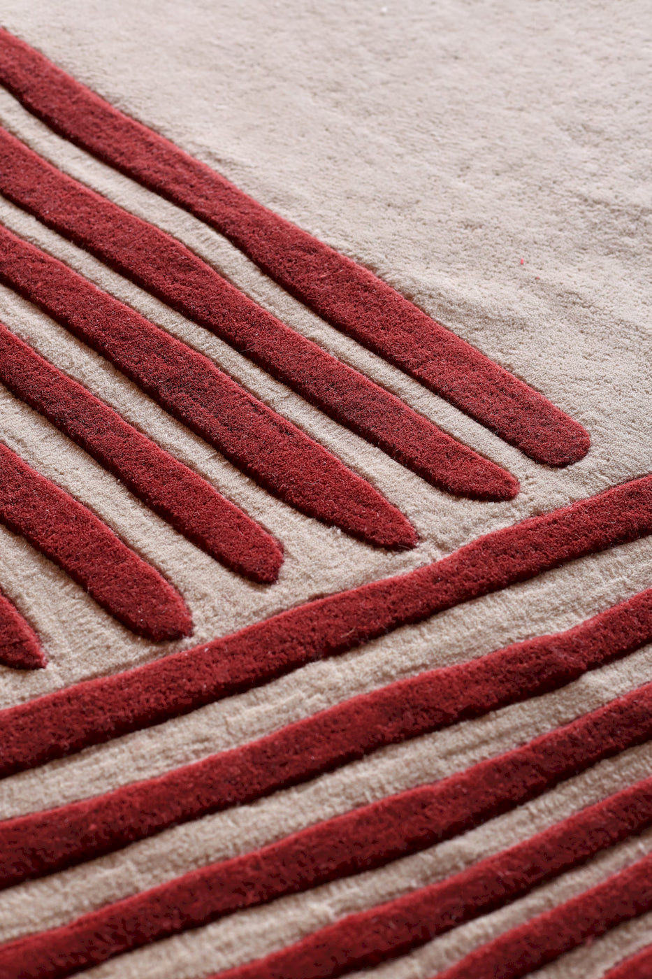 Modern red line pattern wool area rug on neutral background